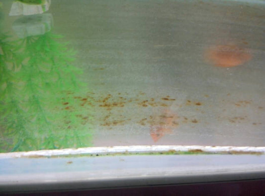 How can iron stains be effectively removed from a glass aquarium?